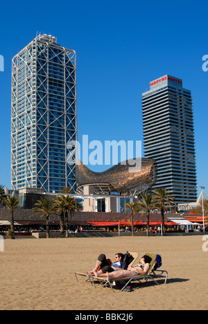 Lucertole da mare a Barceloneta Beach con Frank Gehry s pesce Peix scultura Mapfre Tower Building e Hotel Arts Barcelona Spagna Foto Stock