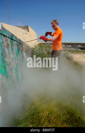 Un uomo che pulisce graffiti a Brighton Marina utilizzando acqua calda pressurizzata Foto Stock