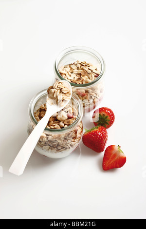 Muesli con yogurt e fragole in piccoli vasetti di vetro Foto Stock