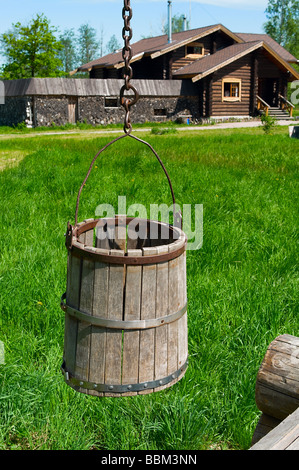 Disegnare in legno e nella zona rurale con shadoof. Erba verde intorno ad esso. Casa in legno in background. Villaggio russo. La Russia Foto Stock