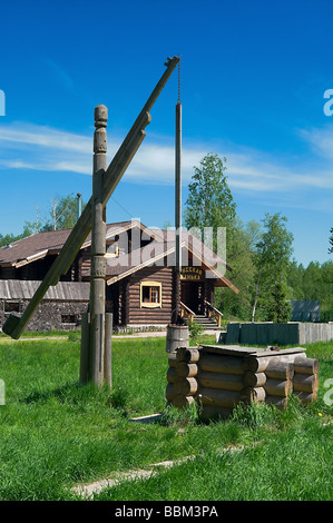 Disegnare in legno e nella zona rurale con shadoof. Erba verde intorno ad esso. Casa in legno in background. Villaggio russo. La Russia Foto Stock