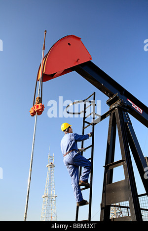 Lavoratore di arrampicata martinetto della pompa con olio impianto di perforazione in background a Canadian Petroleum scoprire museo nel Devon Alberta Canada Foto Stock