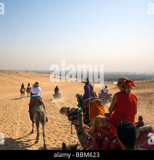 I turisti a cavallo di cammelli e ATV (dune buggy) sulla sabbia vicino al Pyradmids, Giza, il Cairo, Egitto Foto Stock