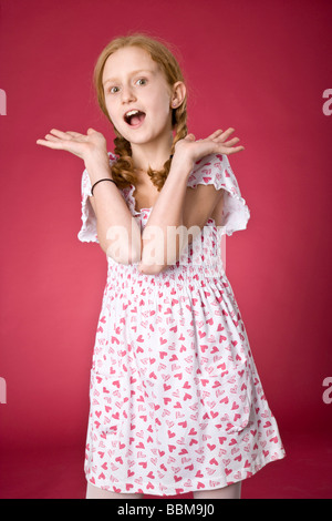 I Capelli rossi ragazza con trecce che indossa un vestito estivo di fronte a uno sfondo rosso Foto Stock