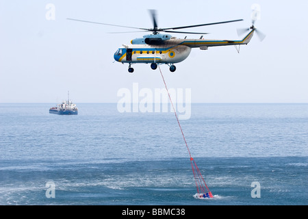 Fire elicottero prendere acqua dal mare al suo serbatoio speciale Foto Stock