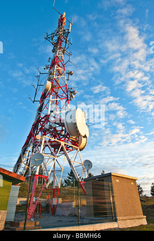 Torre di telecomunicazioni con antenne paraboliche su un cielo blu Foto Stock