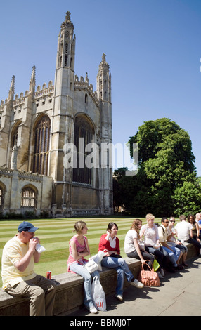 I turisti seduti su una parete da Kings College Chapel, Kings Parade, su una soleggiata giornata d'estate, Cambridge, Regno Unito Foto Stock