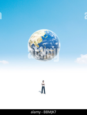 Statuetta di uomo in piedi sotto il globo (Composito Digitale) Foto Stock