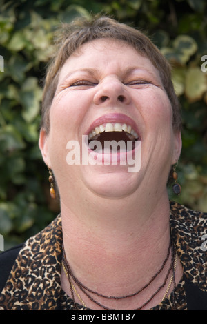 Una donna con la testa appoggiata indietro ridendo in modo incontrollabile Foto Stock