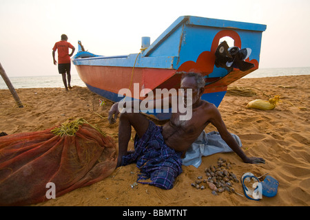 Anziano pescatore indiano riposa dopo la cernita attraverso la sua cattura di gusci. Questo giorno ha catturato il pesce n. Foto Stock