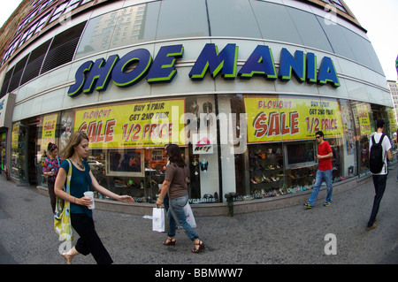 Agli acquirenti di passare una scarpa Mania store pubblicità le sue vendite in Union Square a New York Foto Stock