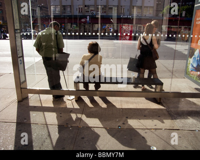 Piloti di attendere per un autobus in un bus Cemusa shelter in New York quartiere di Chelsea Foto Stock