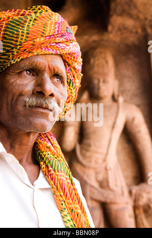 Un uomo che indossa un turbante in Karnataka, India. L'uomo si erge di fronte a una delle grotte scolpite a Badami. Foto Stock