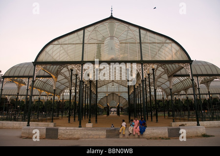 Una famiglia indiana sedersi sotto il palazzo di cristallo in Lalbagh Giardino Botanico di Bangalore, India. Foto Stock