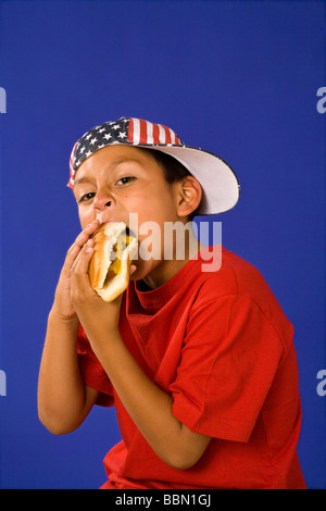 Ritratto di giovane ragazzo ispanico 7-9 anno indossando il 4 luglio stelle strisce hat holiday mangiare hotdog signor © myrleen pearson Foto Stock