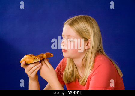 Ritratto di ragazza di mangiare un trancio di pizza, studio shot tagliare fuori il signor © Myrleen Pearson Foto Stock