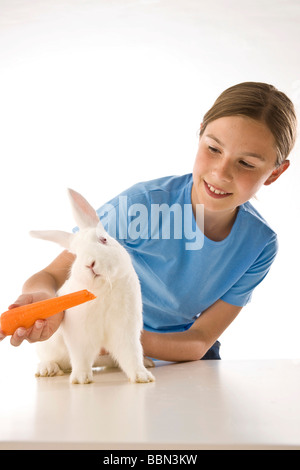 Una ragazza alimentando il suo coniglietto bianco con una carota Foto Stock