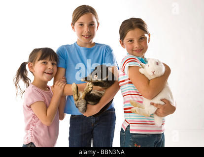 Un gruppo di tre ragazze, le due più grandi tenendo un coniglio in le loro braccia Foto Stock