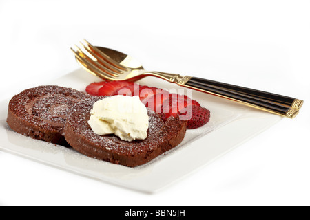 Il cioccolato svizzero di ruolo con panna e fragole su una piastrina con cucchiaio e forchetta Foto Stock
