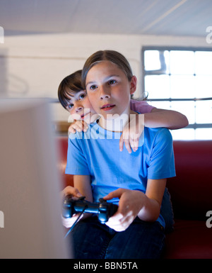 Una scolaretta e una ragazza kindergarten intensamente la riproduzione di un video gioco Foto Stock