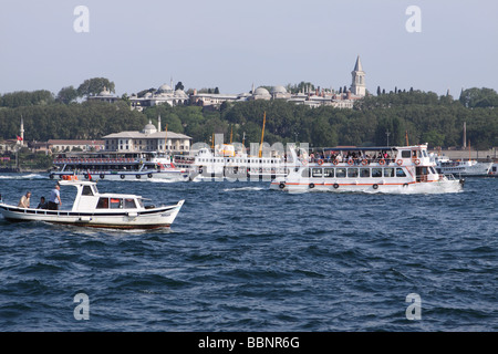 Istanbul Turchia occupato Golden Horn harbour scena locale con la barca da pesca e traghetti passando il Topkapi Palace Foto Stock