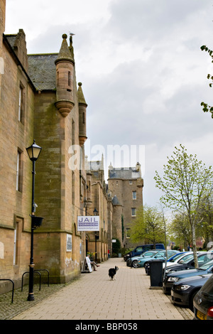 Main Street a Dornoch, east coast, Sutherland, Scozia mostra Dornoch Castle Hotel, la vecchia prigione e sheepdog sul percorso Foto Stock