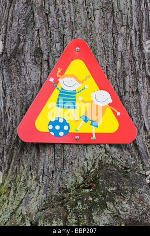 Segno, attenzione, bambini che giocano, sul tronco di albero Foto Stock