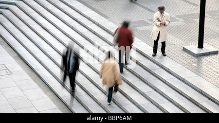 Gli uomini in abito nero a camminare in una strada di Tokyo nella zona di Shinjuku, motion blur, un uomo in piedi ancora altre quelle in movimento Foto Stock