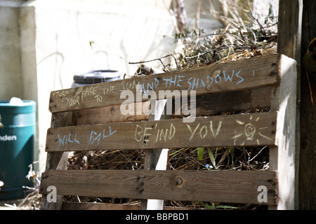 Messaggio scritto in Chalk sul cancello di legno, 'Girare la tua faccia al sole e le ombre cadranno dietro di te' Foto Stock