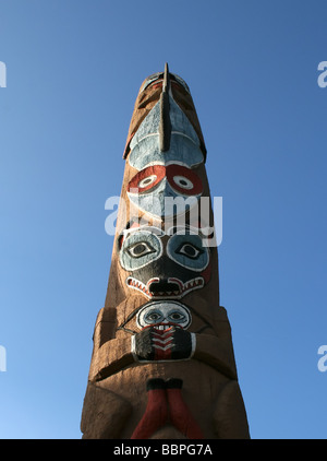 Un nativo del totem pole che mostra un numero di coloratissimi dèi contro un cielo blu Foto Stock