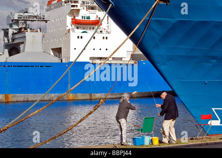 I pescatori di linea nella parte anteriore di un inserito in barca da carico nel porto commerciale, LE HAVRE, SEINE-MARITIME (76), in Normandia, Francia Foto Stock