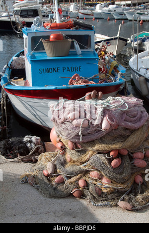 Una classica vecchia barca da pesca con reti e galleggia in Giglio Porto la luce di entrata per l'Isola del Giglio o Isola del Giglio Foto Stock