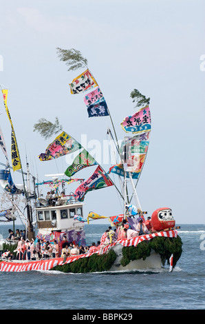 Barca da pesca decked out in banner colorati accelerando attraverso le onde durante l'Ose Matsuri festival nei pressi di Numazu Giappone Foto Stock