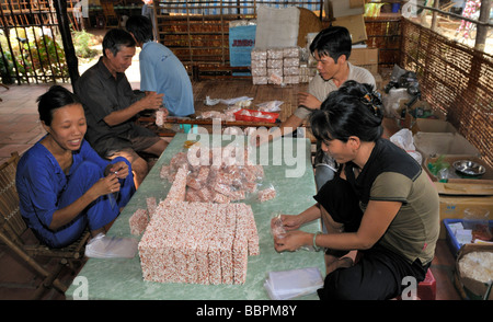 Due uomini e due donne confezionamento riso soffiato dolci, pasticceria fabbrica, Vinh Long, Delta del Mekong, Vietnam, sud-est asiatico Foto Stock