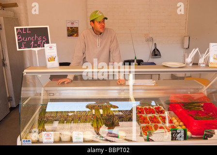 Una farm locale shop negozio vendita di asparagi freschi Fragole e libera la gamma uova con il negoziante in background nel Regno Unito Foto Stock