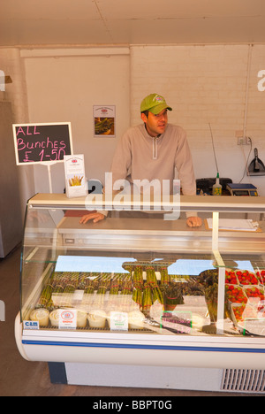 Una farm locale shop negozio vendita di asparagi freschi Fragole e libera la gamma uova con il negoziante in background nel Regno Unito Foto Stock