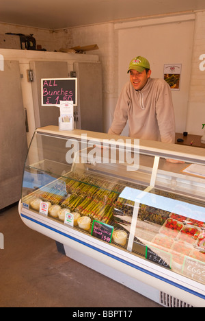 Una farm locale shop negozio vendita di asparagi freschi Fragole e libera la gamma uova con il negoziante in background nel Regno Unito Foto Stock