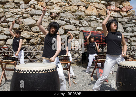 Una ragazza adolescente batterista troupe libbre il ritmo sulla tradizionale giapponese tamburi taiko Foto Stock