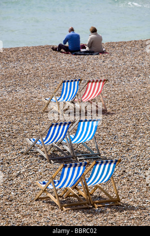 Giovane seduto sulla spiaggia accanto a sdraio Brighton Inghilterra Foto Stock