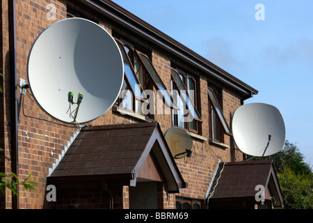 Grandi antenne paraboliche fissato al di fuori di una fila di case nel Regno Unito Foto Stock