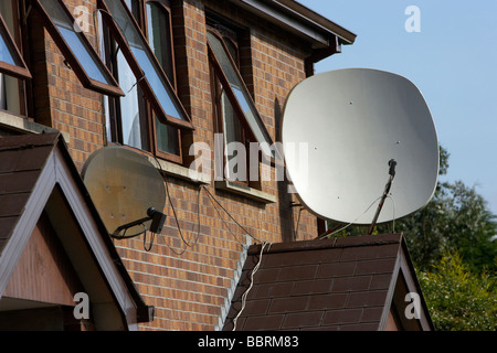 Grandi antenne paraboliche fissato al di fuori di una fila di case nel Regno Unito Foto Stock