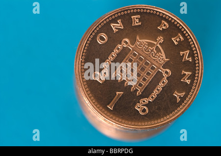 Pila di lucido nuove un penny monete contro uno sfondo blu Foto Stock
