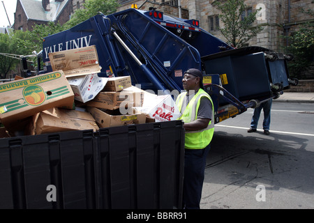 Un uomo si prepara a spostare un contenitore riempito con cartone riciclabile in un camion della spazzatura alla Yale University di New Haven CT STATI UNITI D'AMERICA Foto Stock