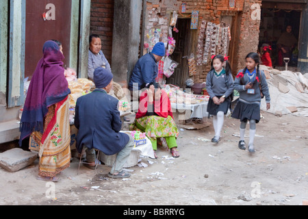 Kathmandu, Nepal. Studentesse passando quartiere negozio che vende articoli da emporio. Foto Stock