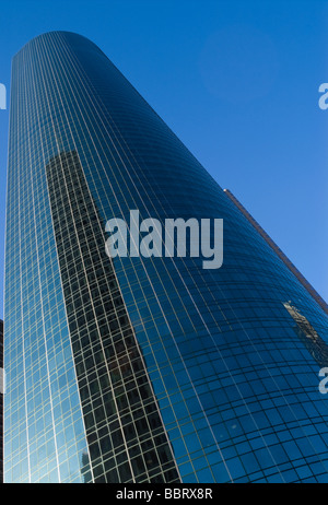 Grattacielo con riflessione sulle finestre in vetro blu contro un cielo chiaro Foto Stock