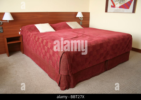 Letto king size in una camera d'hotel con legno copriletto e moquette sui pavimenti Foto Stock