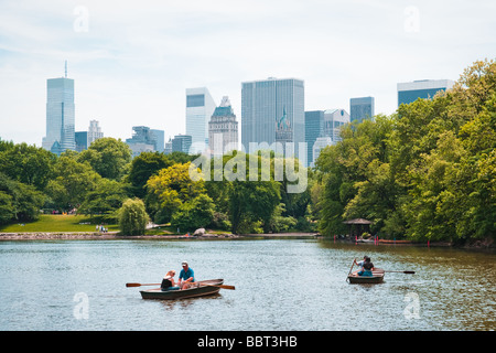 Le coppie canottaggio in affitto barche di riga in un lago nel parco centrale contro la Manhattan skyling in background su un giorno d'estate. Foto Stock