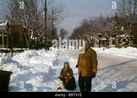 Un padre stoppa il suo piccolo ragazze su una slitta, San Lambert, Montreal 1956 Foto Stock