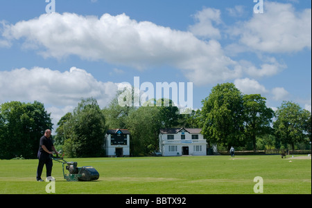 Un groundsman tende il fuori campo lato al cricket ground, Roberts Park, Saltiare, West Yorkshire Foto Stock