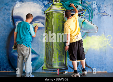 Gli uomini dipinto graffiti presso il centro di skateboard South Bank di Londra UK Europa Foto Stock